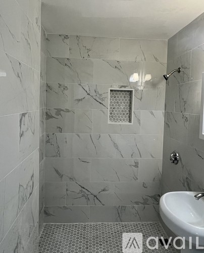 A bathroom with a marble tile wall and a white sink.