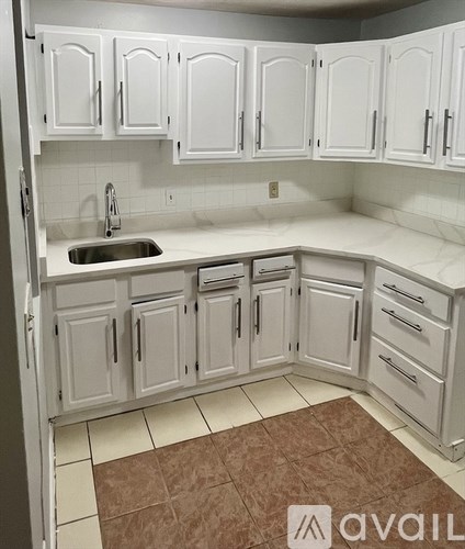 A kitchen with white cabinets and a brown rug on the floor.