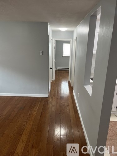 A hallway with wooden floors and white walls.