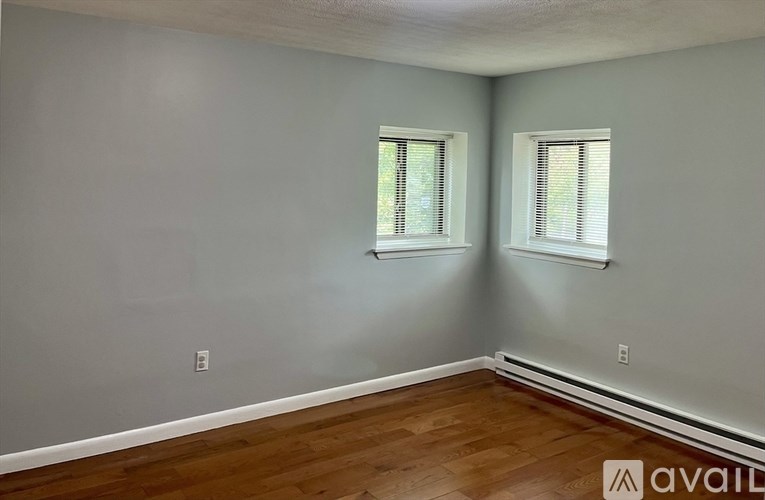 A room with wooden floors and two windows.