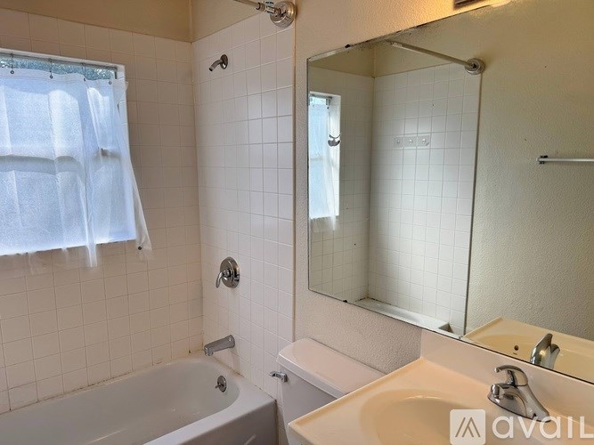 A bathroom with a white tub, sink, and mirror.
