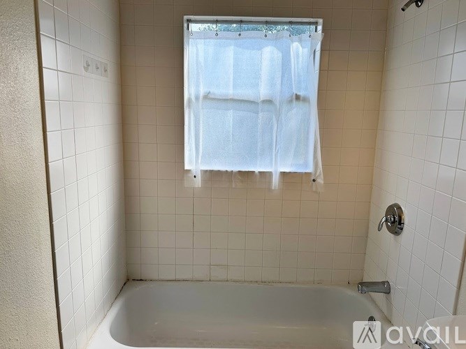 A white tiled bathroom with a tub and shower.