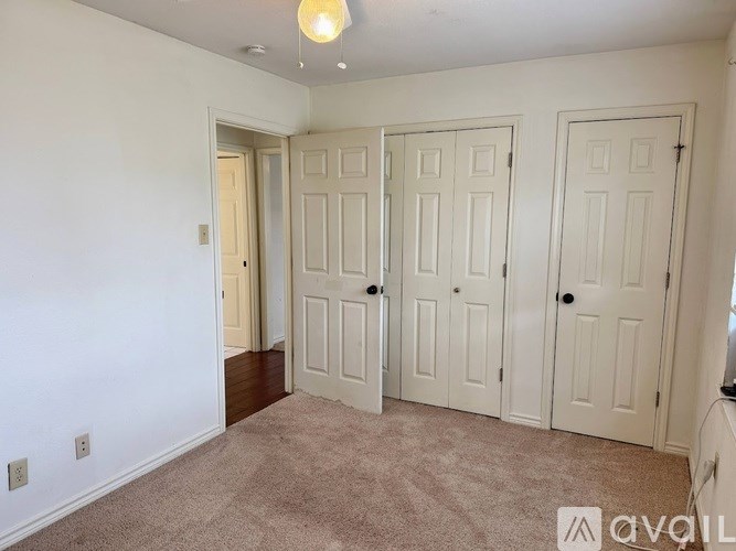 A room with three white doors and a carpeted floor.