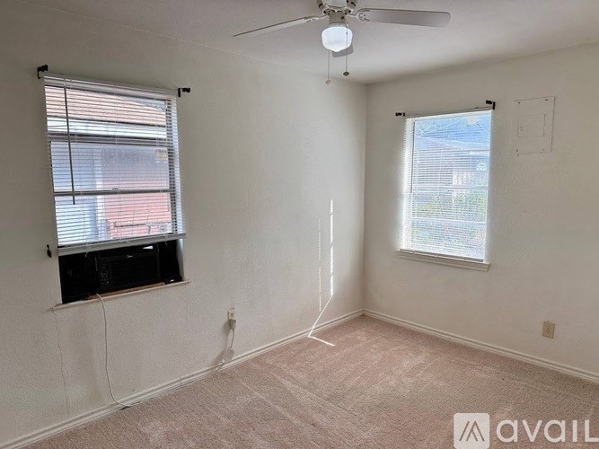 A room with a ceiling fan and two windows.
