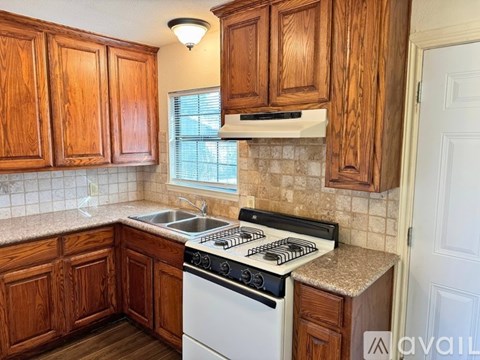 A kitchen with wooden cabinets and a white stove top oven.
