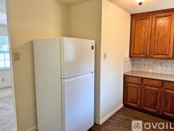 A white refrigerator in a kitchen with wooden cabinets.