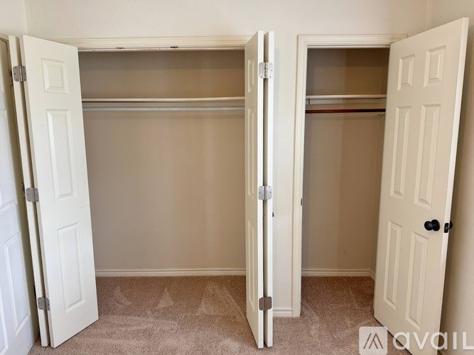Two white closet doors open to reveal empty shelves.