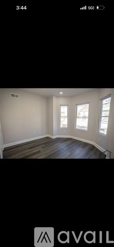 A room with wooden flooring and two windows.