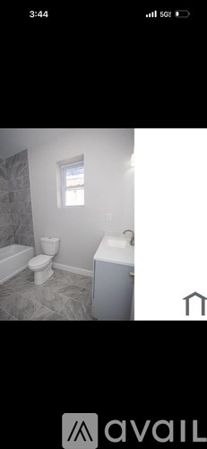 A bathroom with a toilet, sink, and a window.