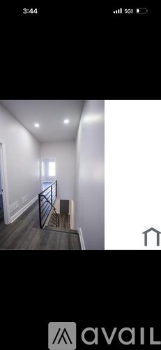 A staircase with a metal railing leads to a brightly lit room.