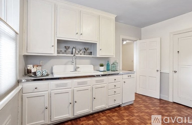 A kitchen with white cabinets and a wooden floor.