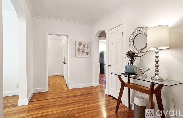 A hallway with a wooden floor and white walls.
