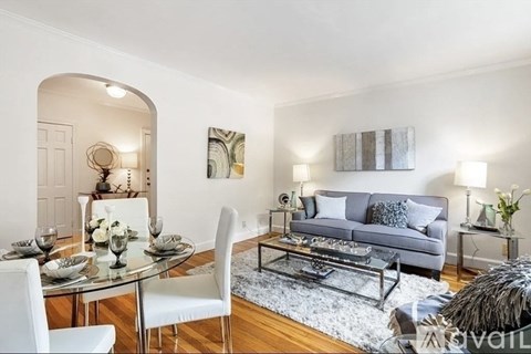 A modern living room with a glass dining table and white chairs.