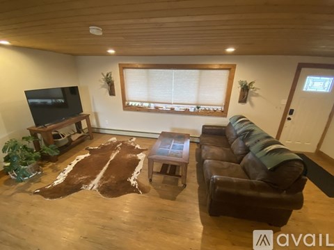 A living room with a cowhide rug and a brown leather couch.
