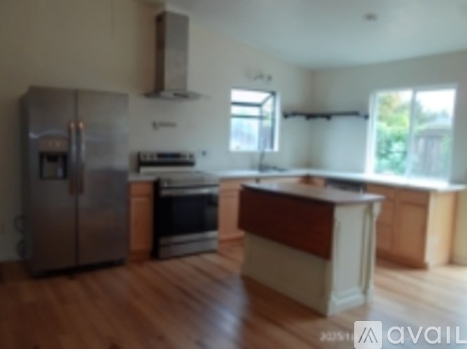A kitchen with a refrigerator, oven, and a window.