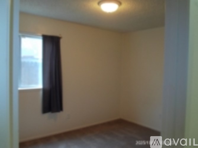 A room with a window and a curtain hanging on the wall.