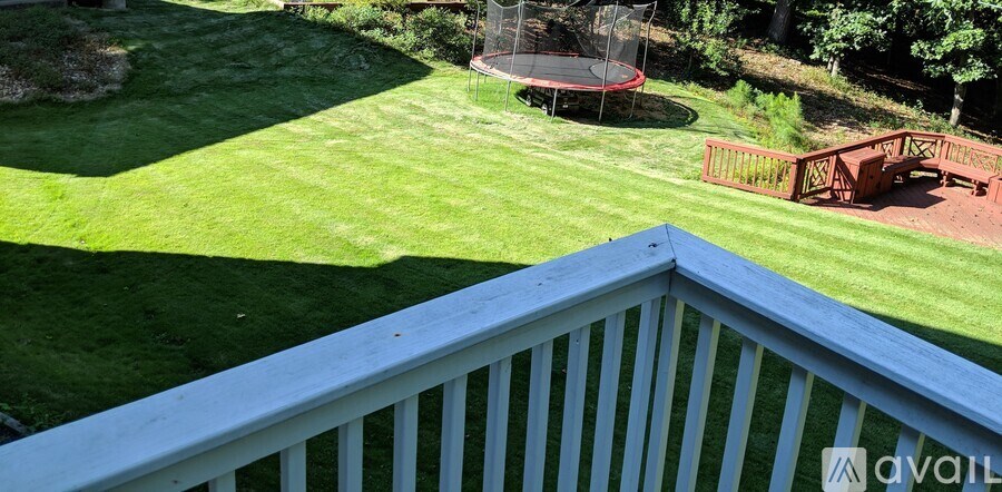 A backyard with a trampoline and a deck.