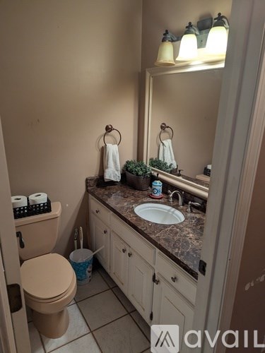 A bathroom with a toilet, sink, and mirror.