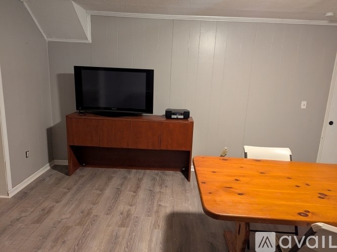 A room with a wooden table and a television on a wooden stand.
