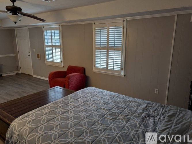 A bedroom with a bed, a chair, and a ceiling fan.