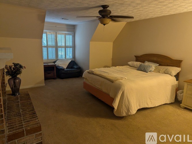A bedroom with a bed, a ceiling fan, and a window with blinds.