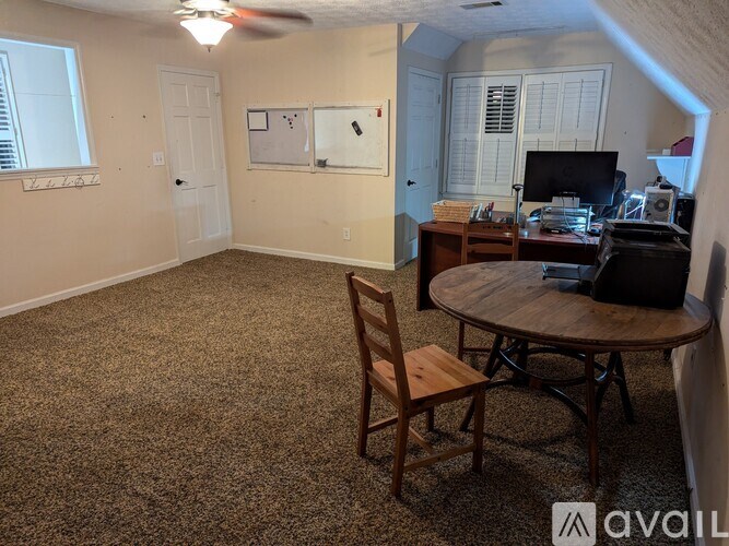 A room with a table, chairs, and a fan.