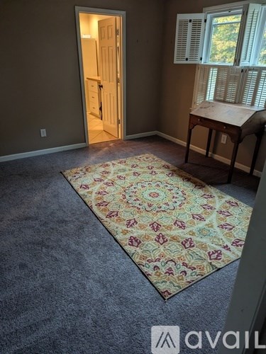A room with a rug and a table with a window.
