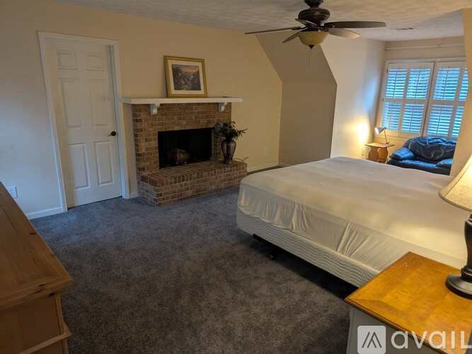 A bedroom with a bed, a fireplace, and a ceiling fan.