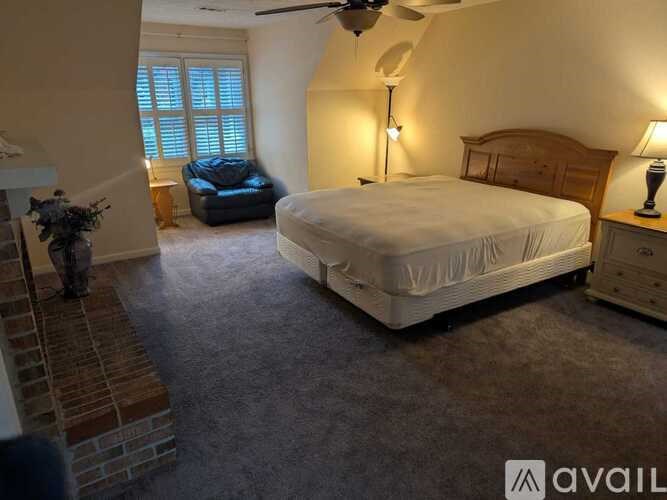 A bedroom with a bed, dresser, and a fan.