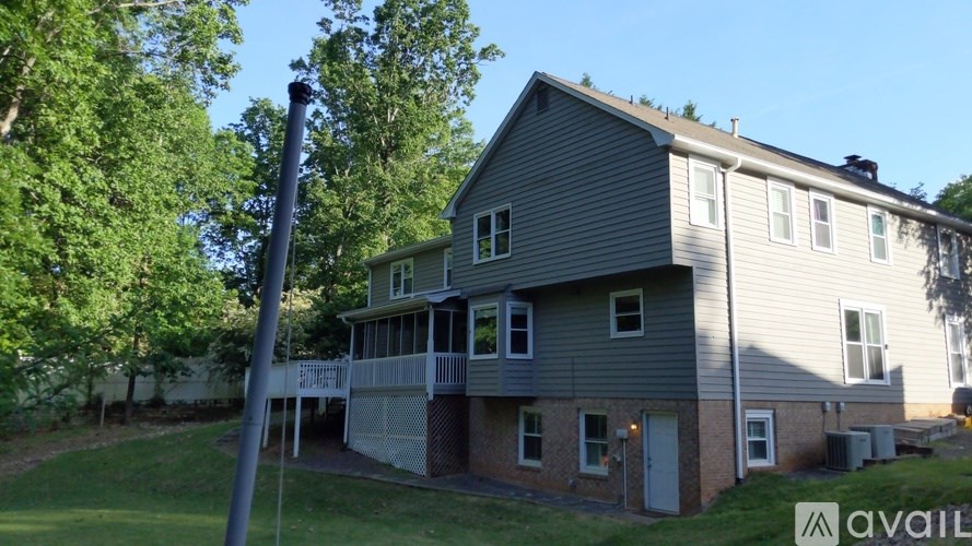 A house with a grey siding and a white door is available for rent.