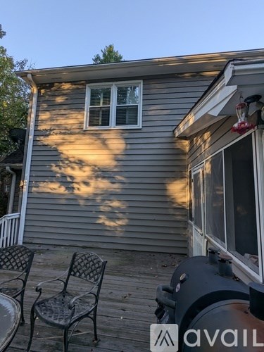 A house with a grey siding and a window with black shutters.