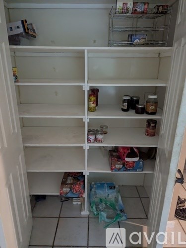 A pantry with white shelves and a few items on them.