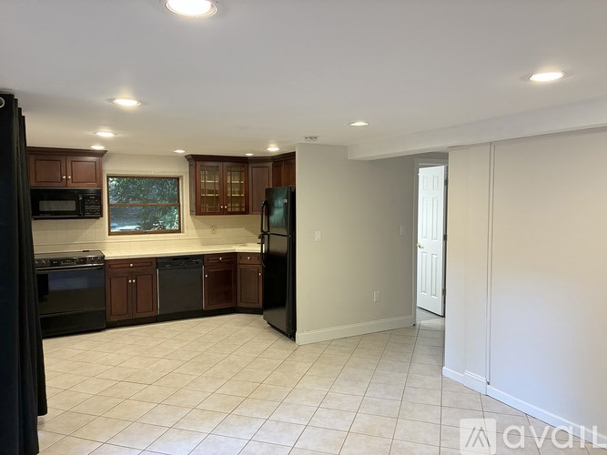 A kitchen with black appliances and brown cabinets.