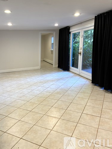 A spacious room with tiled flooring and a sliding glass door.