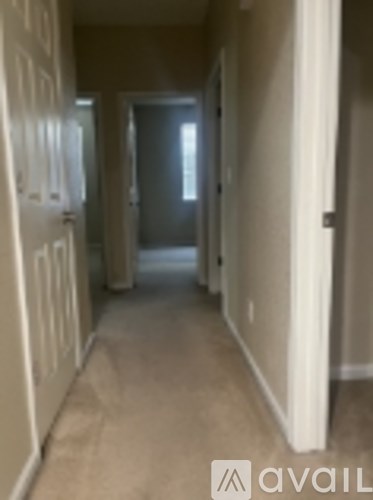 A hallway with white doors and carpeted flooring.
