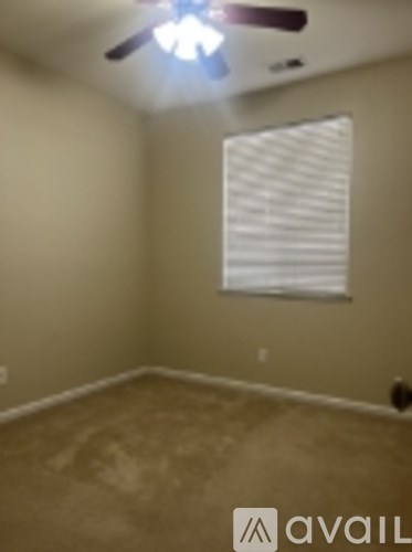 A room with a ceiling fan and a window with blinds.