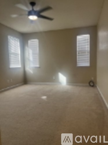 A room with a ceiling fan and two windows.