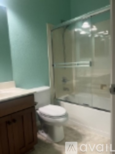 A white toilet sits in a bathroom with a glass shower door.
