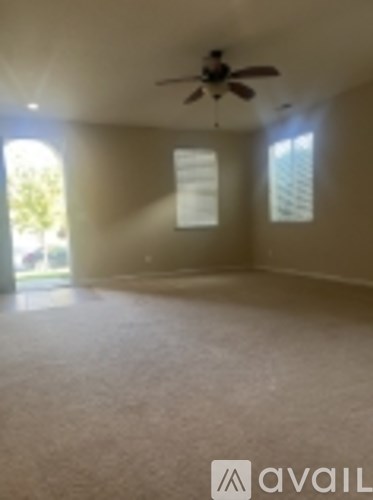 A room with a ceiling fan and two windows.