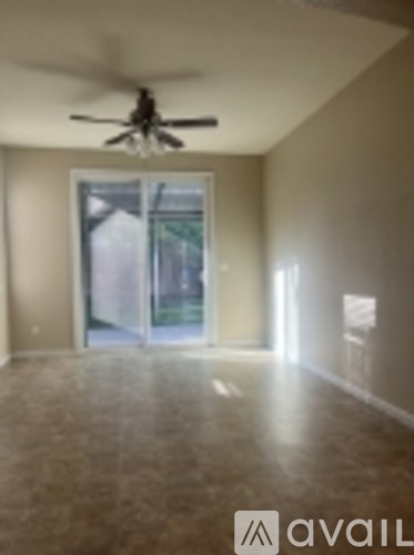 A room with a ceiling fan and a large window.