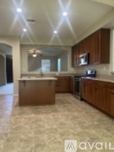 A kitchen with wooden cabinets and a marble floor.