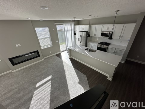 A spacious living room with a fireplace and a kitchen area in the background.