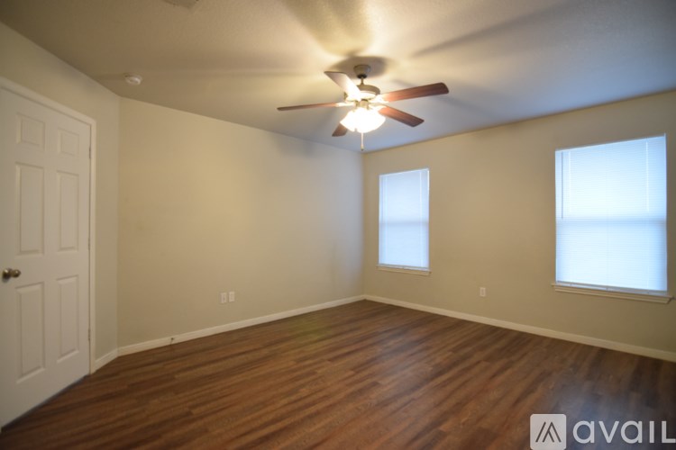 A room with a ceiling fan and wooden flooring.