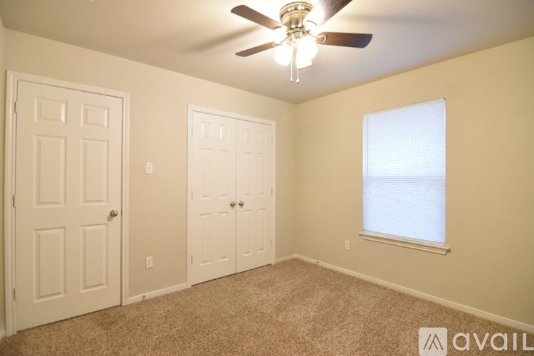A room with a ceiling fan and two doors.
