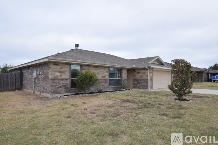 A house with a brown roof and a stone wall is available for rent.