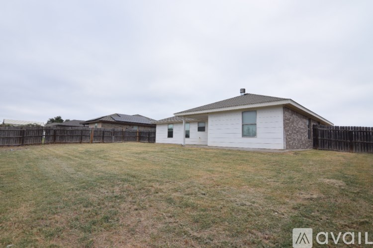 A house with a white exterior and a brown roof is surrounded by a black fence.
