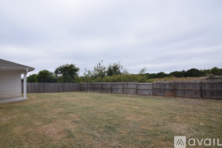 A backyard with a wooden fence and a house in the background.