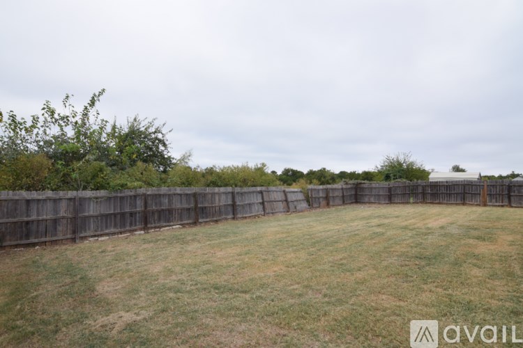 A backyard with a wooden fence and a grassy field.