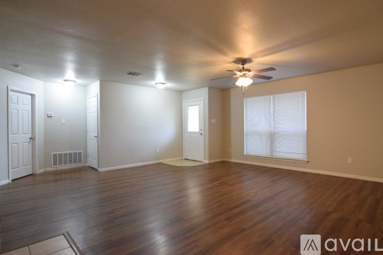 A spacious room with wooden floors and a ceiling fan.