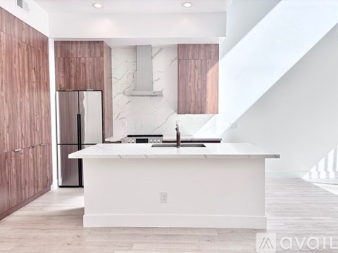 A modern kitchen with a white countertop and wooden cabinets.